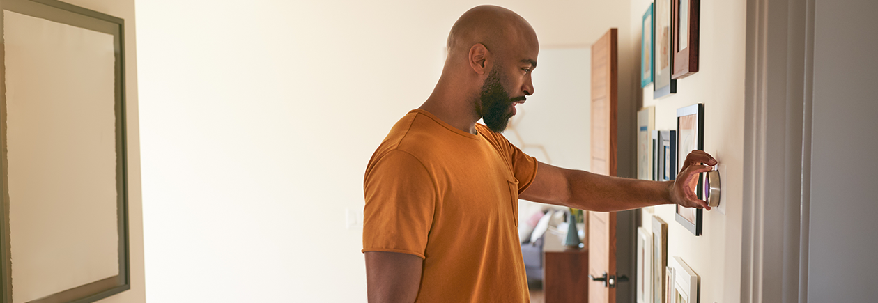 Man Conserving Energy through checking his thermostat